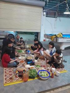 a group of people sitting around a table with food at Villa GinnHouse Mộc Châu 1 in Mộc Châu