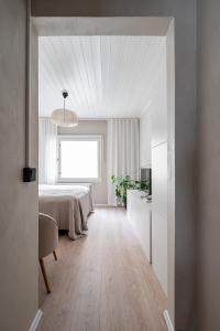 a white bedroom with a bed and a window at Lovely Studio in Pispala in Tampere