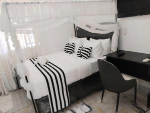 - une chambre avec un lit blanc et des oreillers noirs et blancs dans l'établissement Skybeach apartment, à Kisumu