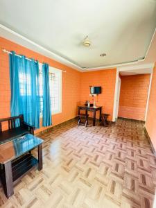 an empty living room with blue curtains and a wooden floor at The Stream View Villas Wayanad in Vythiri