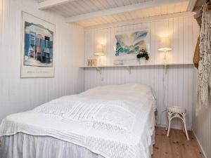 a white bedroom with a bed and a chair at Holiday home Blokhus LXX in Blokhus