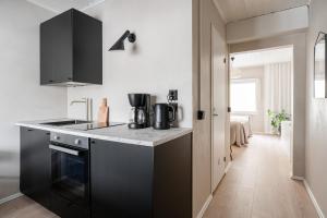 a kitchen with black appliances and a hallway at Lovely Studio in Pispala in Tampere