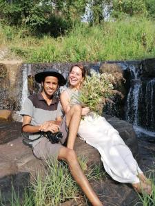 un hombre y una mujer sentados en una roca frente a una cascada en Mountain View Home stay, en Mirigama