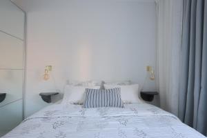 a white bed with a striped pillow on it at Urban Oasis - Two Bedrooms - Balcony - Nearby Metro in Helsinki