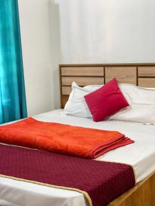 The Stream View Villas Wayanad في فيثايراي: سرير بمناشف ومخدات بيضاء وحمراء