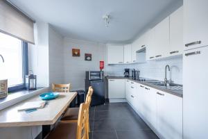 a kitchen with white cabinets and a table and chairs at Appartementen The Place 2 Beer in Bullange