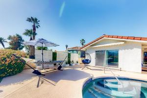 パームデザートにあるPalm Desert Doveの家の隣に椅子とパラソル付きのプールがあります。