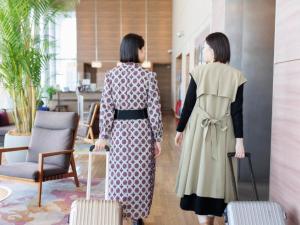 two women walking down a hallway with their luggage at Hotel Resol Trinity Hakata in Fukuoka