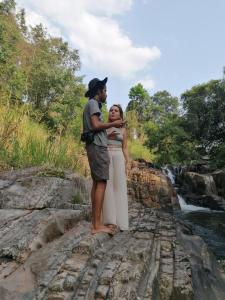 a man and a woman standing on a rock near a river at Mountain view home stay in Mirigama