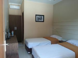 een hotelkamer met 2 bedden, een bureau en een kamer bij Roemah kita hotel in Ngaglik