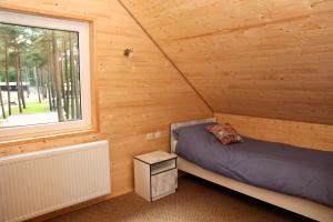 a bedroom in a log cabin with a bed and a window at Blue Resort Ostrowo in Ostrowo +83 photos