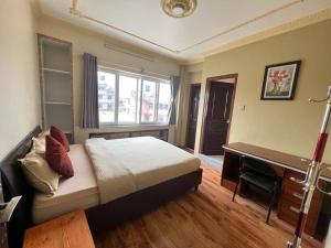 a bedroom with a bed and a desk and a window at Shine Homestay Famille Francophone - Shine Home and Apartment in Kathmandu
