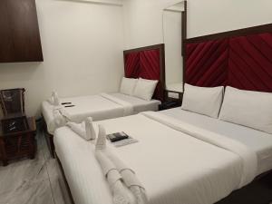 two beds in a hotel room with white sheets at AR Residency in Mumbai