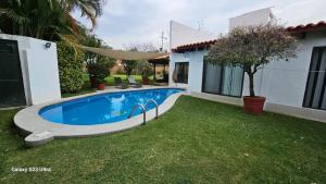 a swimming pool in a yard next to a house at Casa de 1 nivel con alberca en fraccionamiento las Fincas. in Jiutepec