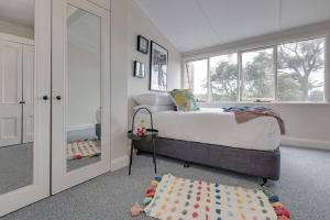 een slaapkamer met een bed en een groot raam bij Cute Heritage Home with Balcony close to the City in Sydney