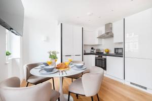 a kitchen and dining room with a table and chairs at Fitzrovia with Balcony - CityApartmentStay in London