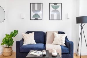 a blue couch in a living room with pictures on the wall at Fitzrovia with Balcony - CityApartmentStay in London