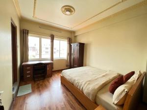 a bedroom with a bed and a desk and a window at Shine Homestay Famille Francophone - Shine Home and Apartment in Kathmandu