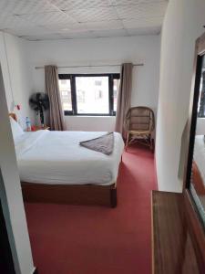 a bedroom with a bed and a chair and a window at Good Hotel in Bandīpur