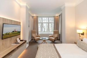 a hotel room with a bed and a tv at HOTEL am STRAND in Kühlungsborn