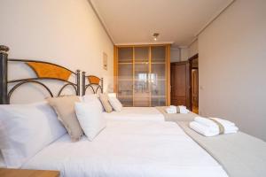 a bedroom with two white beds with white pillows at Tenderina Apartamento in Oviedo