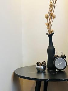 un tavolo con un vaso nero, un orologio e una ciotola di Modern Contemporary 1BR Fully Furnished Condo with Balcony at Prisma Residences a Manila