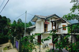 a white house with a fence in front of it at Cool Breeze guest inn in Bandarawela