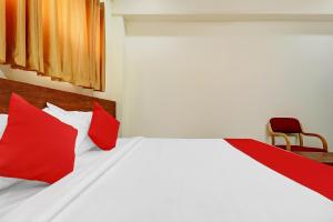 - une chambre avec un lit doté d'oreillers rouges et d'une chaise dans l'établissement Super OYO Hotel Silver House Near Mantri Square Mall, à Bangalore