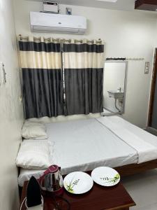 Habitación con 2 camas y 2 platos en una mesa. en Temple View Home Stay en Tiruvannāmalai