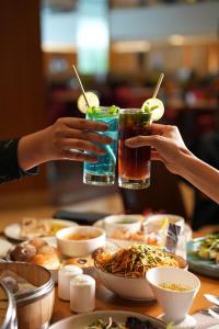 two people are holding drinks at a table with food at Courtyard by Marriott Bhopal in Bhopal