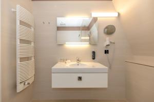 a white bathroom with a sink and a mirror at HOTEL am STRAND in Kühlungsborn +88 photos
