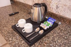 a tray with a coffee pot and cups on a counter at Airport Grand Travel Inn in New Delhi