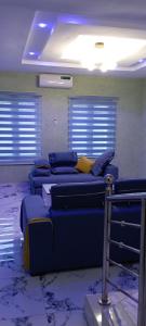 a room with blue couches in a room with windows at WestMore Court a.k.a The Family House in Ibadan