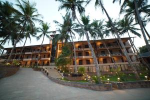 a building with palm trees in front of it at Aananda Wellness and Resorts in Dharmastala