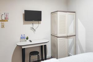a bedroom with a desk and a tv on the wall at RedDoorz Syariah near Transmart Jambi in Paalmerah