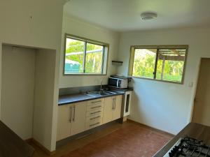 a small kitchen with a sink and two windows at Farnborough Stay in Yeppoon