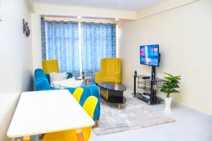 Dala Suites في Kakamega: غرفة معيشة مع كراسي صفراء وتلفزيون