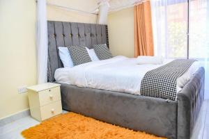 Dala Suites في Kakamega: غرفة نوم مع سرير كبير مع اللوح الأمامي المعدني
