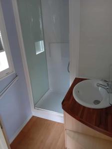 a white bathroom with a shower and a sink at mobilhome 5 couchages in Nages