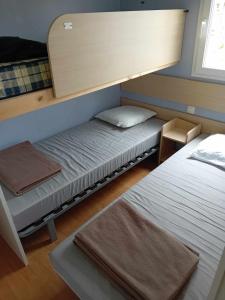 two beds in a small room with a mirror at mobilhome 5 couchages in Nages