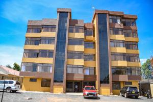 Dala Suites في Kakamega: مبنى فيه سيارات تقف امامه