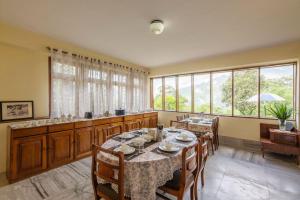 a dining room with a table and chairs and windows at La Ipsing Farm by StayVista, A heritage property in orchards with Mountain views, featuring Outdoor games and A cozy balcony for a memorable stay in Samdong