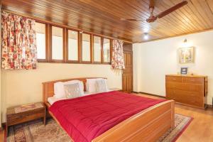 a bedroom with a bed with a red bedspread at La Ipsing Farm by StayVista, A heritage property in orchards with Mountain views, featuring Outdoor games and A cozy balcony for a memorable stay in Samdong