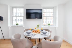 Soho & Fitzrovia with Balcony - CityApartmentStay في لندن: غرفة طعام بيضاء مع طاولة بيضاء وكراسي