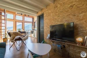 ein Wohnzimmer mit einem TV und einem Tisch in der Unterkunft Gîte cabane insolite Pyrénées in Sauveterre