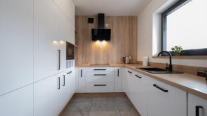 a kitchen with white cabinets and a sink at Apartamenty Sun & Snow Enklawa pod Bieniatką in Szczyrk
