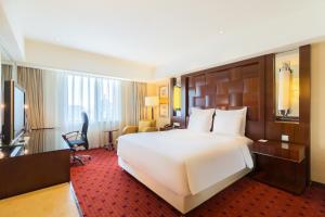 um quarto de hotel com uma grande cama branca e uma secretária em Beijing Pudi Hotel em Pequim