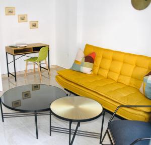 ein Wohnzimmer mit einem gelben Sofa und 2 Tischen in der Unterkunft Haus LIDZBARSKI in Burriana