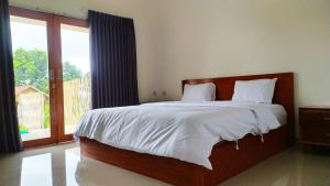a bedroom with a large bed and a large window at Embun Rinjani Homestay in Senaru