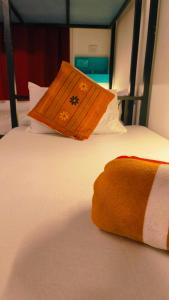 an orange pillow is sitting on a bed at Mitra Hostel in Arambol